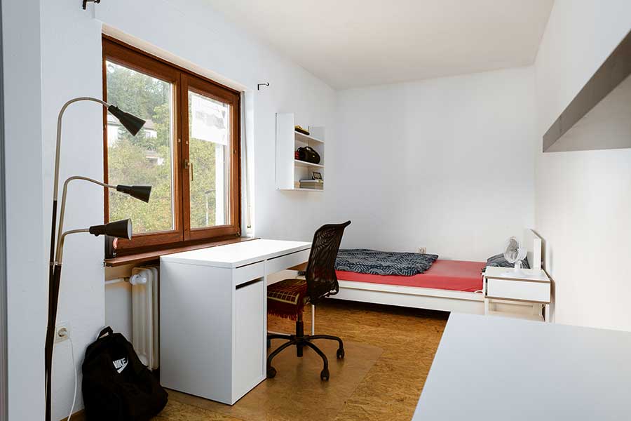 Einzelzimmer mit Bett, Schreibtisch und Regal – funktional eingerichtet für Rückzug und Struktur im Alltag